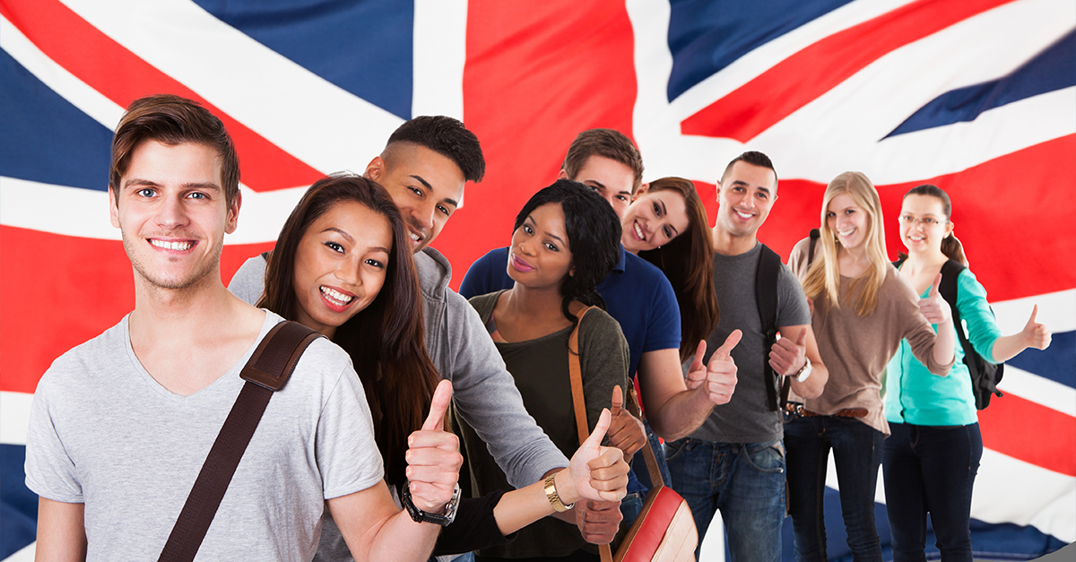Group Of Happy Multi Ethnic Students Standing In Front Of Uk Flag Showing Thumb Up