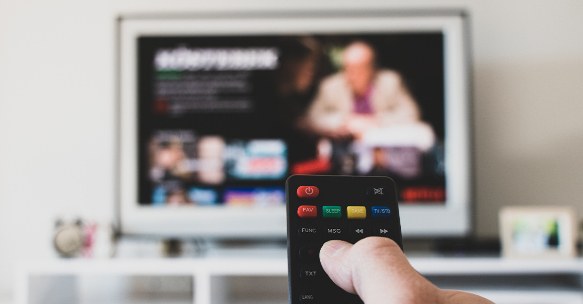 Learning Business English while watching Netflix - blurred TV with Netflix menu in background, foreground hand with remote control in focus while sitting on couch