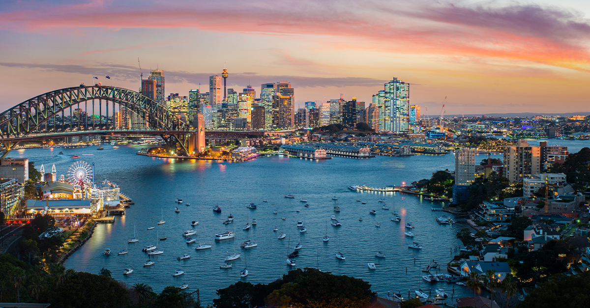 Cityscape image of Sydney, Australia with Harbour Bridge and Sydney skyline during sunset.