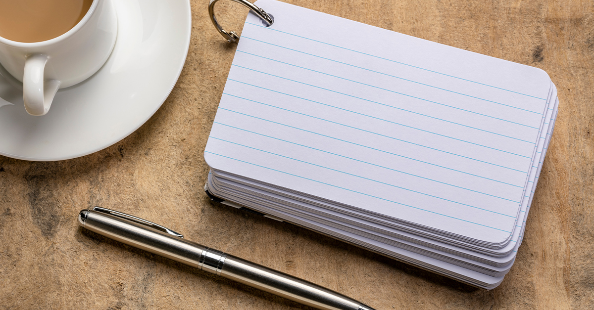 blank index cards bound with a metal ring to use as flashcards with a cup of coffee and a pen