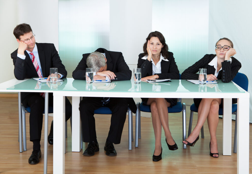 Four bored business people sitting at table
