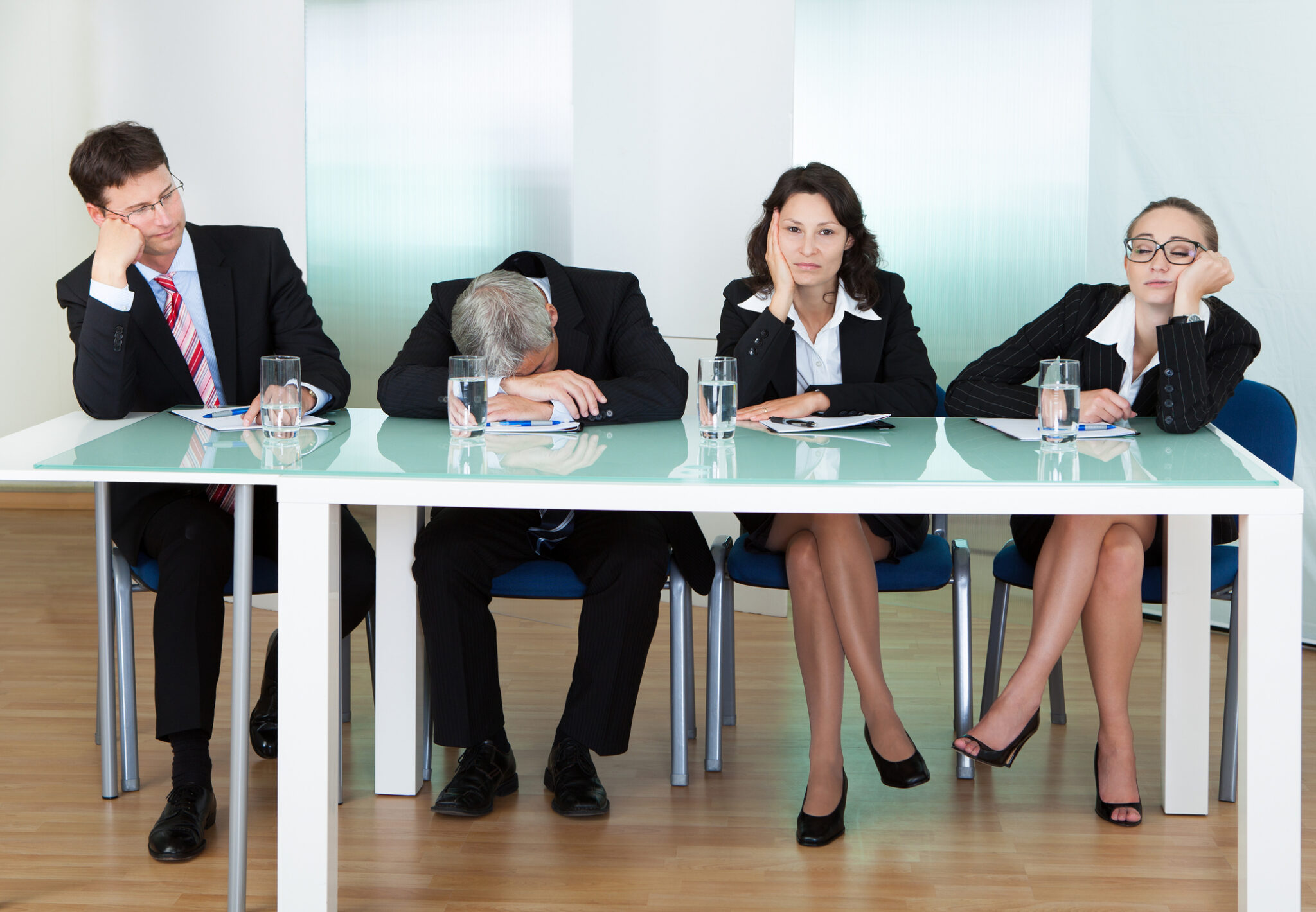 Four bored business people sitting at table