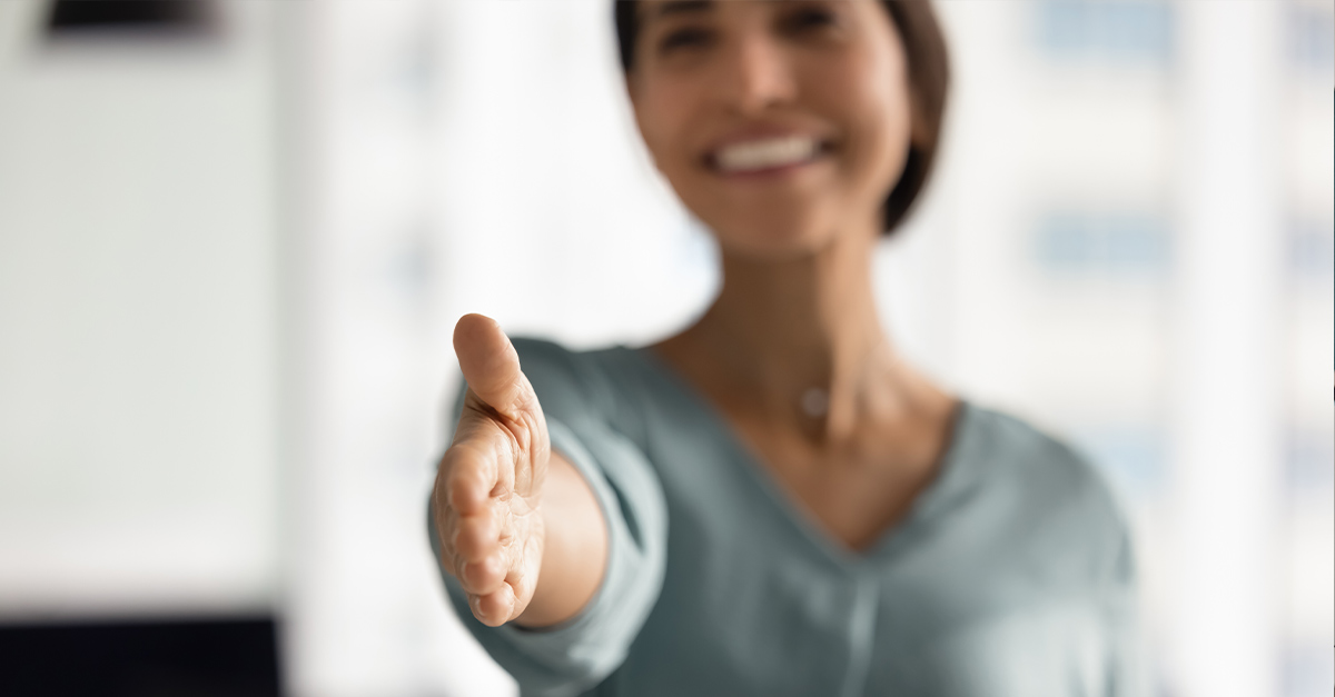 Business woman with outstretched hand in polite greeting, illustrating the blog topic "Why Politeness Can Make or Break a Global Deal"