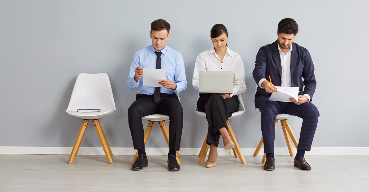 Group of male and female job seekers sitting in row on chairs waiting for job interview | How to Write Your Resume in Spanish