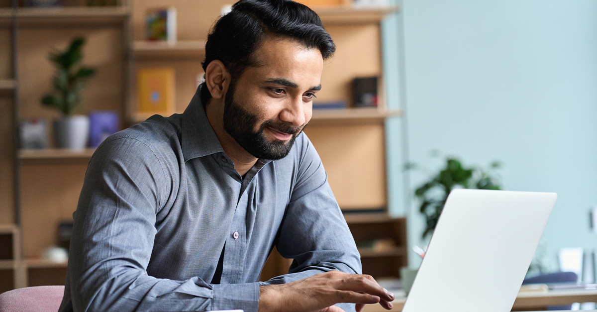 Smiling man working on laptop, illustrating the blog topic Free Resources to Learn Business English
