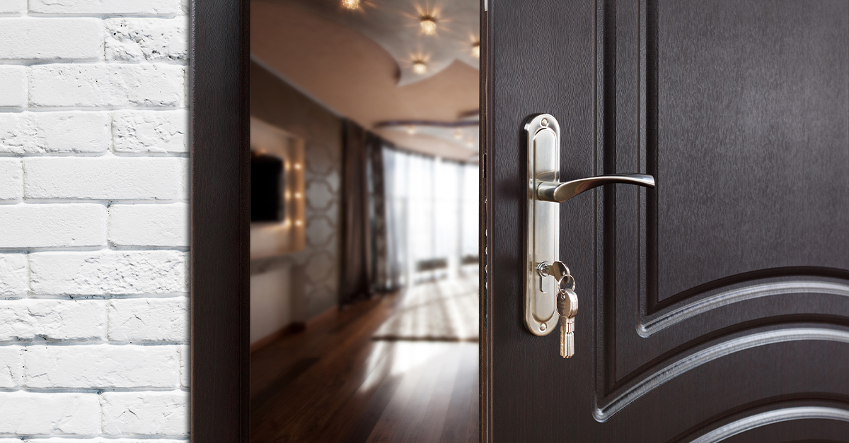 Half-opened front door with keys in lock, showing an empty living room, illustrating the blog topic Reverse Culture Shock: How to Retain Language Skills After Repatriation
