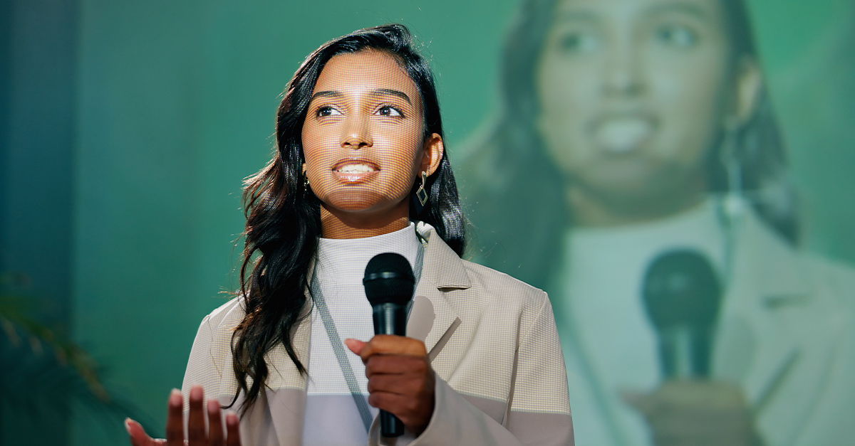 Young professional Indian woman on stage with a microphone giving a corporate presentation on common English pronunciation mistakes