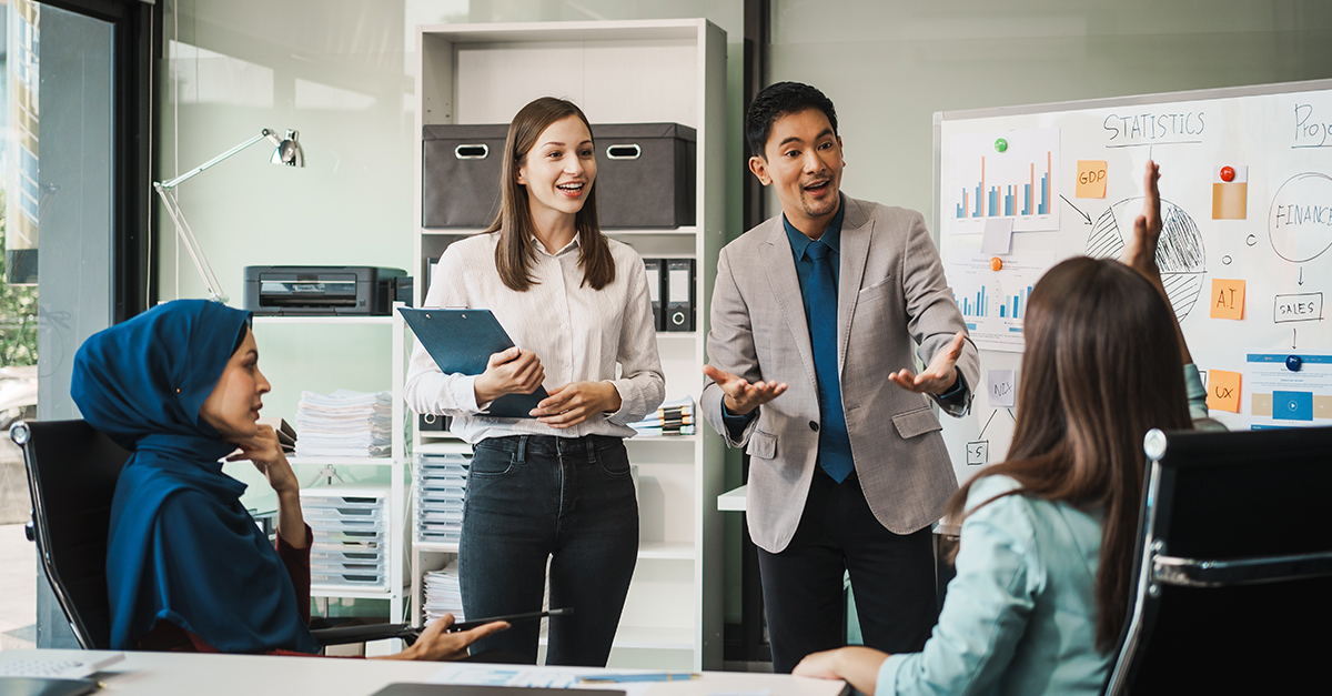 A diverse team, including a middle-aged Asian businessman, Caucasian young businesswoman, Muslim hijab-wearing middle-aged businesswoman, meets in a boardroom showing the impact of language skills on employee satisfaction and job retention