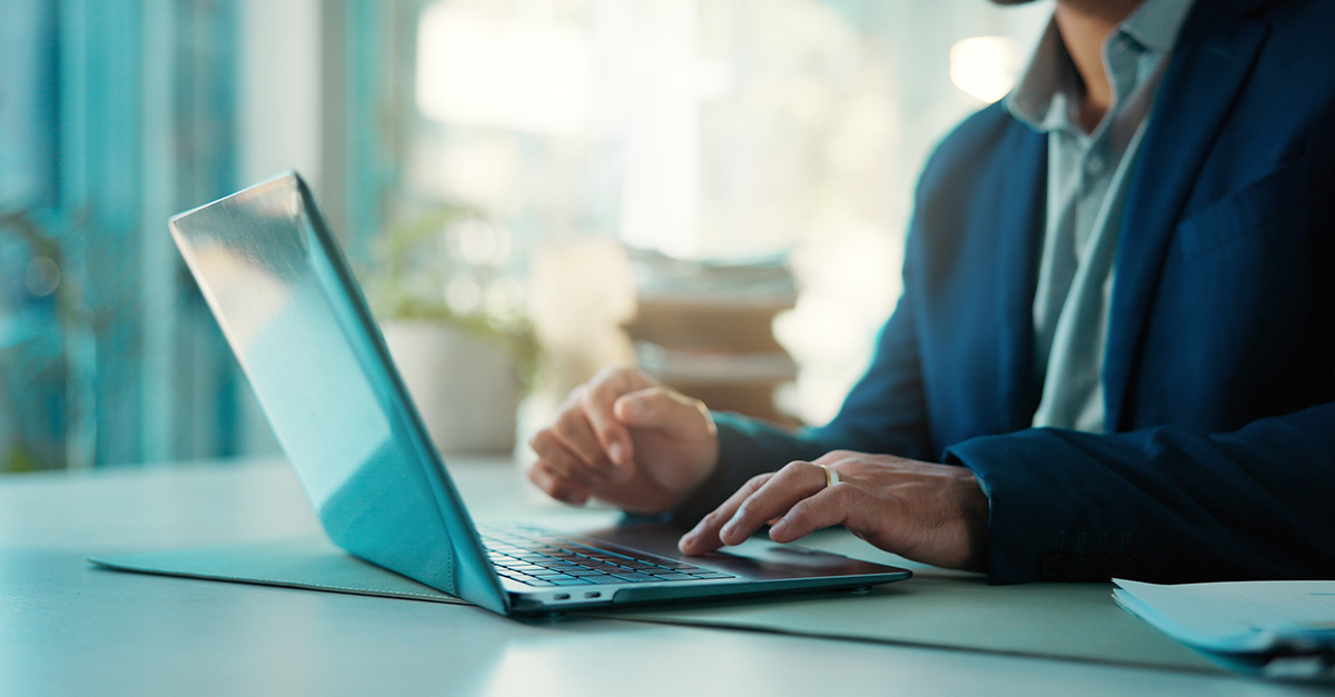 Cropped shot of a business man's hands typing an email on a laptop in an office